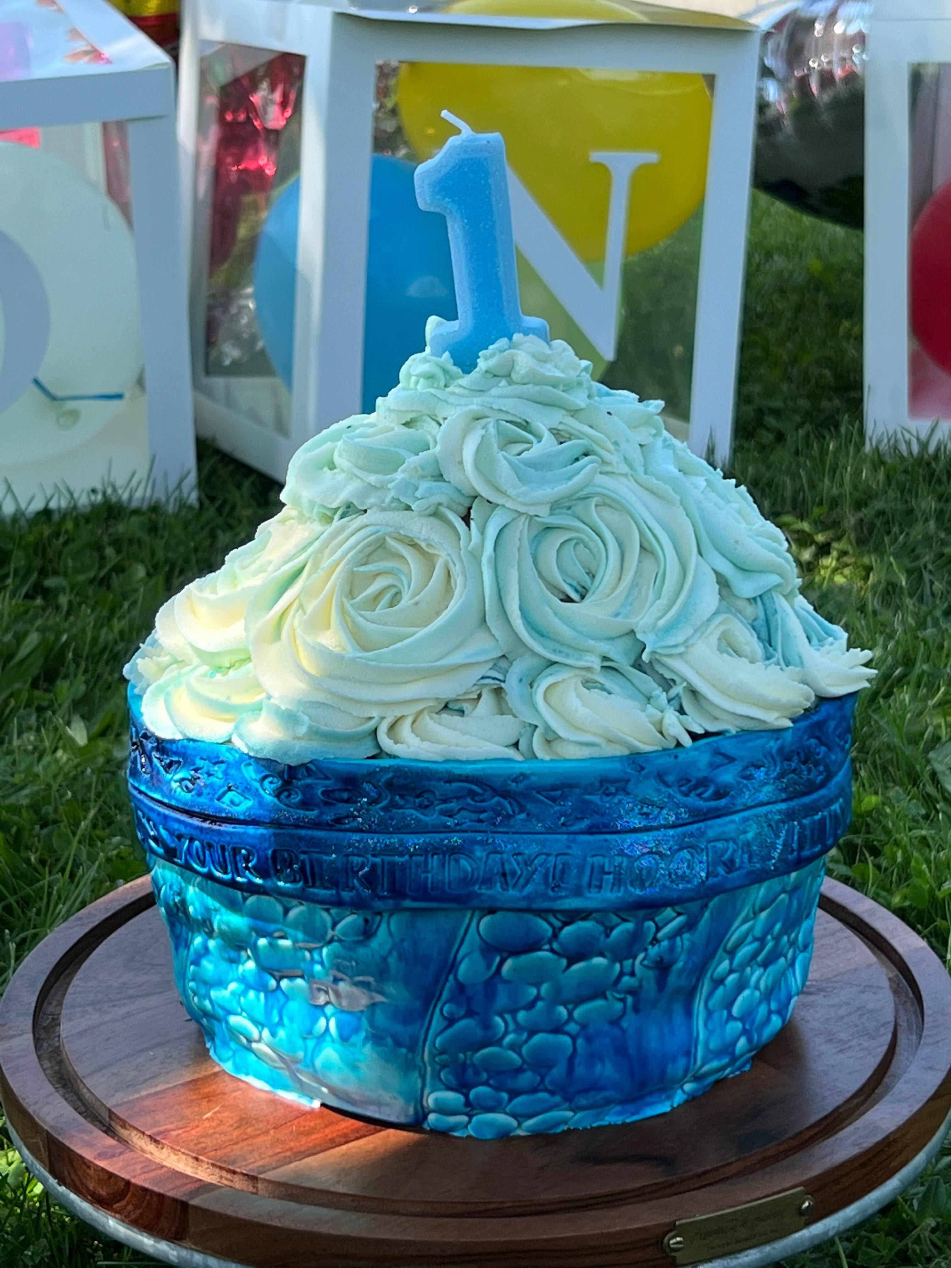 A blue and white cake sitting on top of a wooden plate.